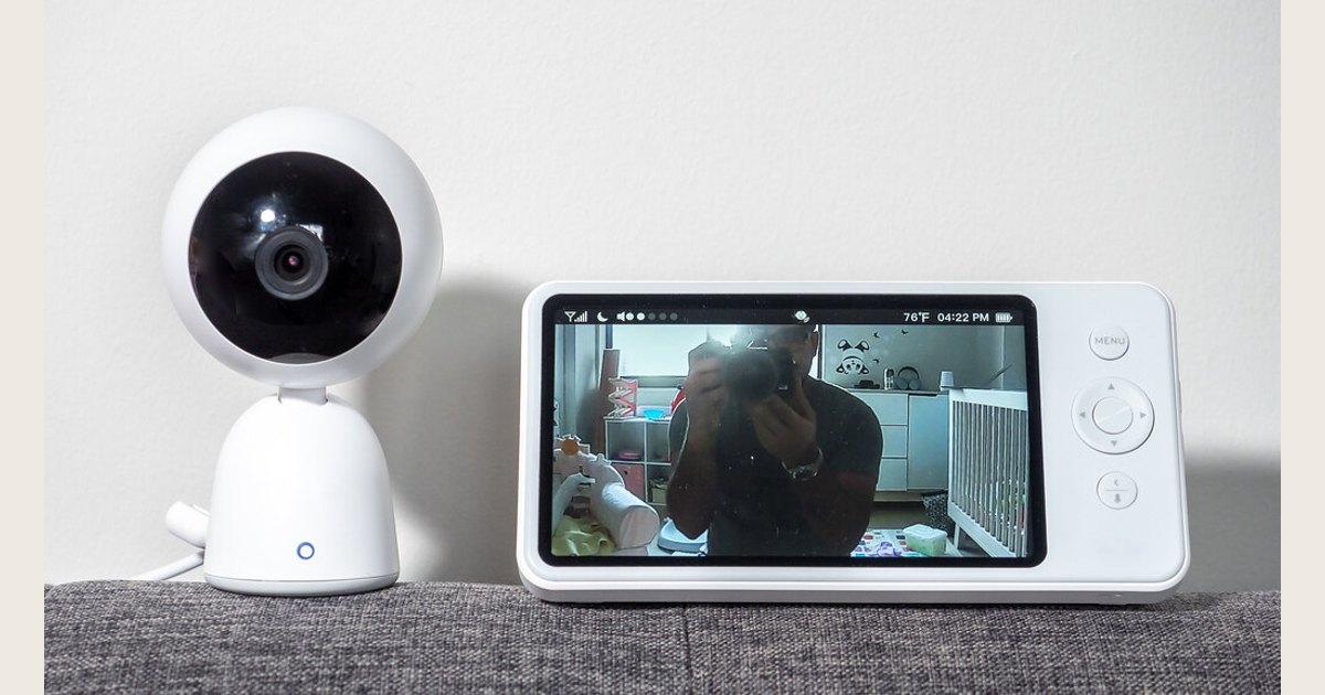 A baby monitor with its screen illuminated sits on a tabletop.